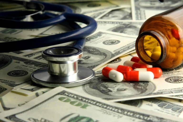 A stethoscope and pills are backgrounded by money to show savings from the payment integrity process