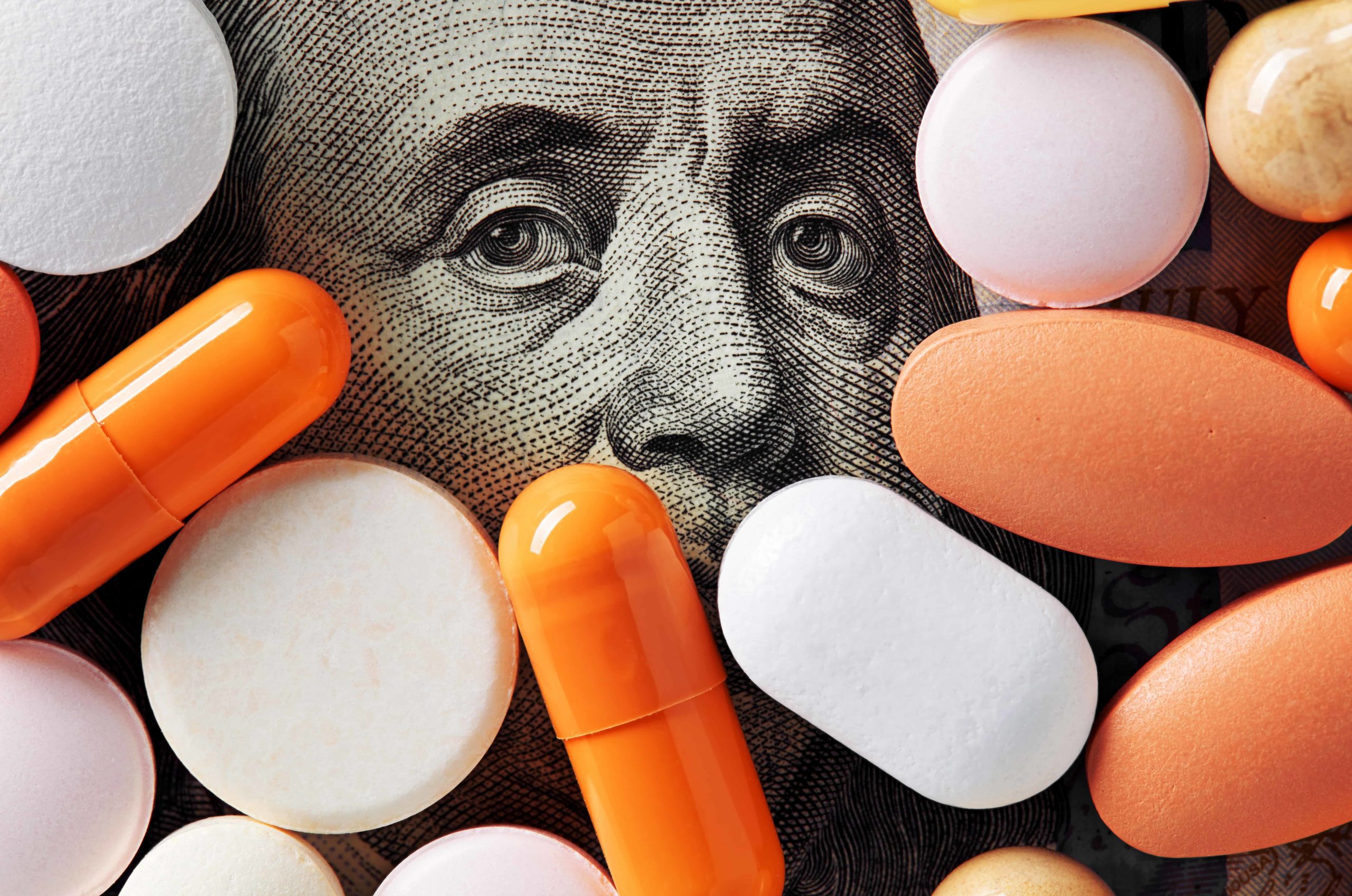 Prescription drugs sit atop a hundred-dollar bill to show savings from using examples of cost containment in healthcare