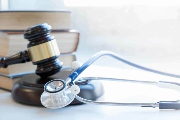 A stethoscope lays atop a gavel on a white desk to visualize how the payment integrity information act of 2019 impacts healthcare