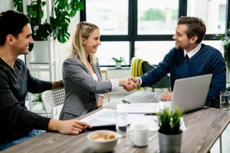 As they enjoy the advantages of TPAs in health insurance, a man and woman shake hands with their third-party administrator over completed paperwork.